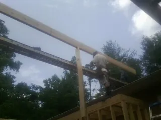 Carpenter setting a ridge beam over a new addition frame — Ice Dam Removal by Roofing Brothers in Tumtum