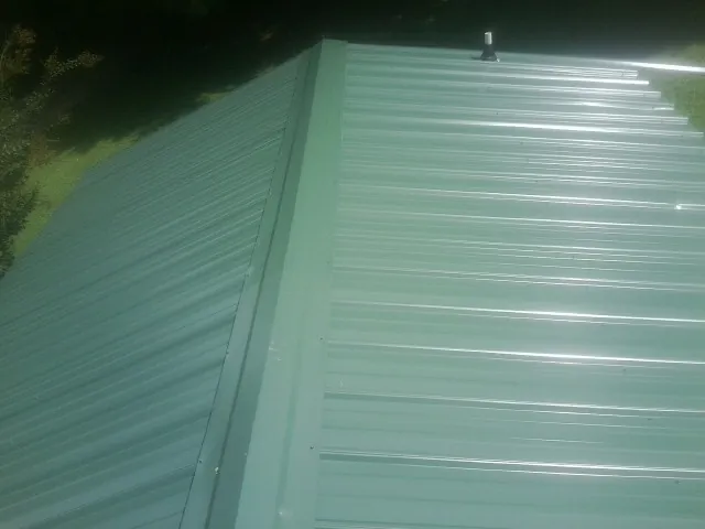 New green metal panels meeting at the ridge of a roof — Flat Roof Repair work by our crew in Tumtum