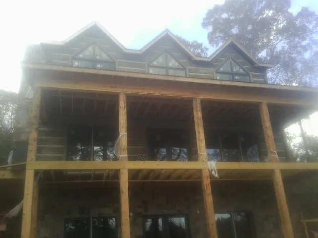 Dormers and porch framing on a large log home under construction — Roof Coating work by our crew in Tumtum