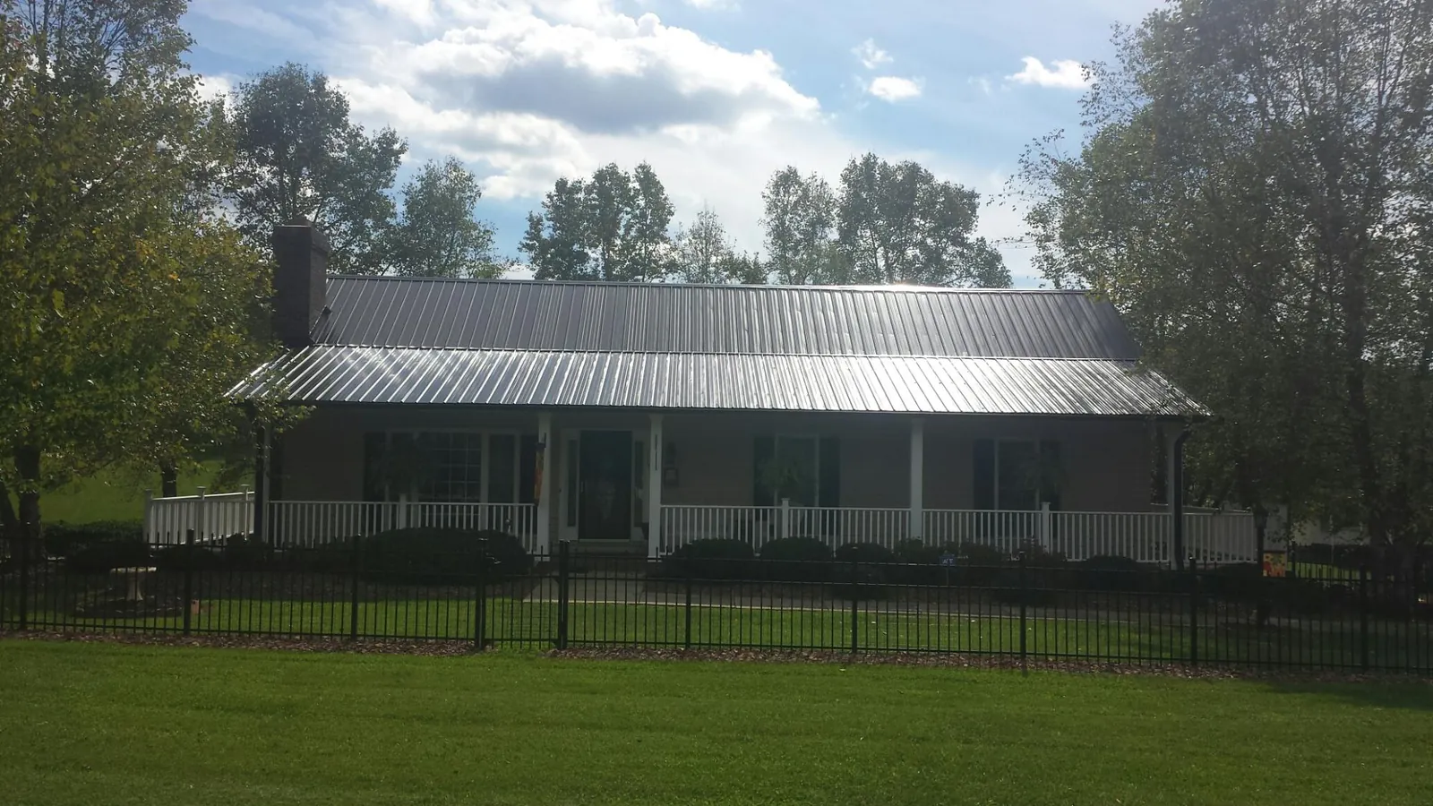 Gray metal roof on a brick ranch with a full width front porch — Gutter Guard Installation work by our crew in Tumtum