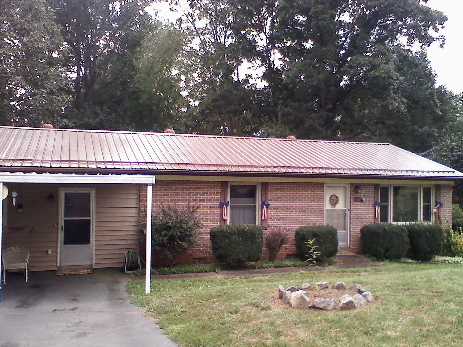 Bronze metal roof and carport on a brick ranch home — Roof Repair work by our crew in Tumtum