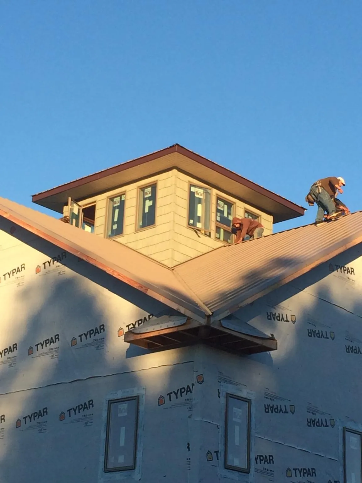 Roofers working around a rooftop cupola on a new metal roof at sunset — Roof Waterproofing in Tumtum by Roofing Brothers